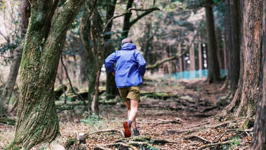 Coureur de dos progressant sur un sentier forestier racineux