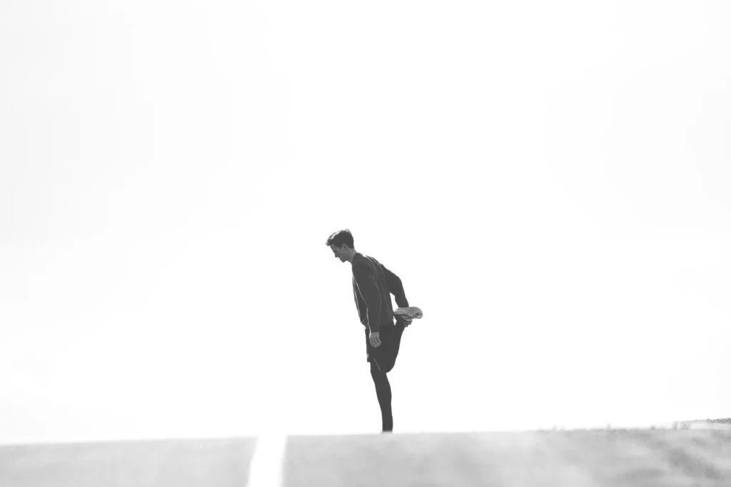 Coureur vu de profil effectuant un étirement avant de partir courir