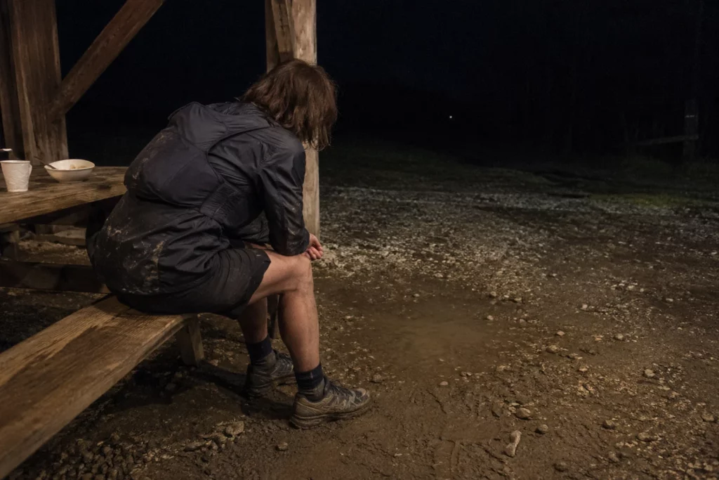 Coureuse fatiguée assise de dos dans un ravitaillement rustique au milieu de la nuit