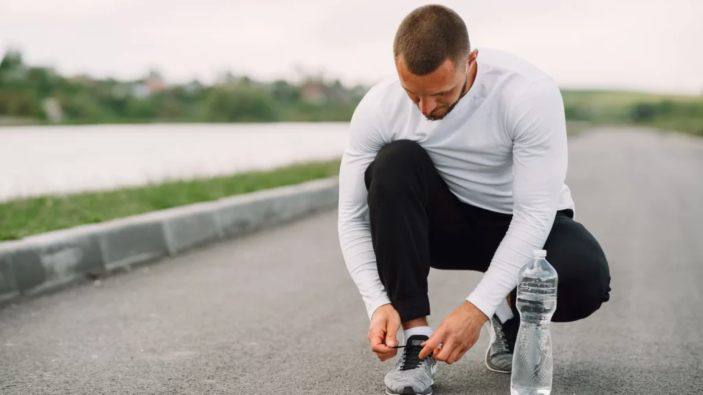 Coureur préparant ses chaussures près d'une bouteille d'eau