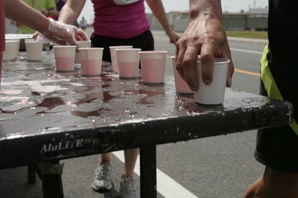 Main d'un coureur prenant une boisson à un poste de ravitaillement