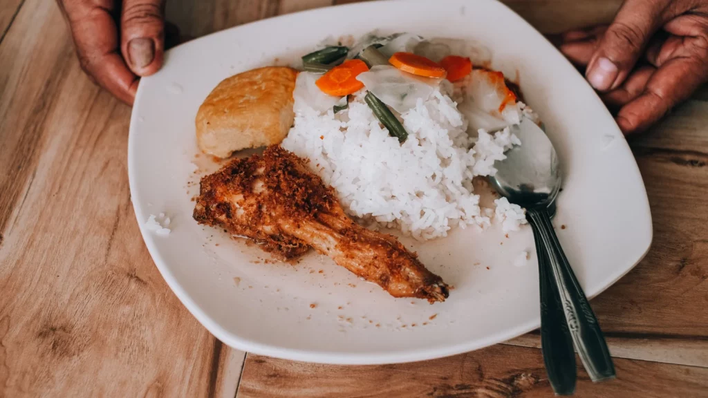 Assiette de riz blanc avec poulet et petite portion de légumes cuits
