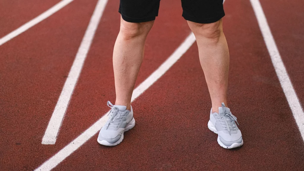 Jambes et chaussures d'un coureur debout sur une piste