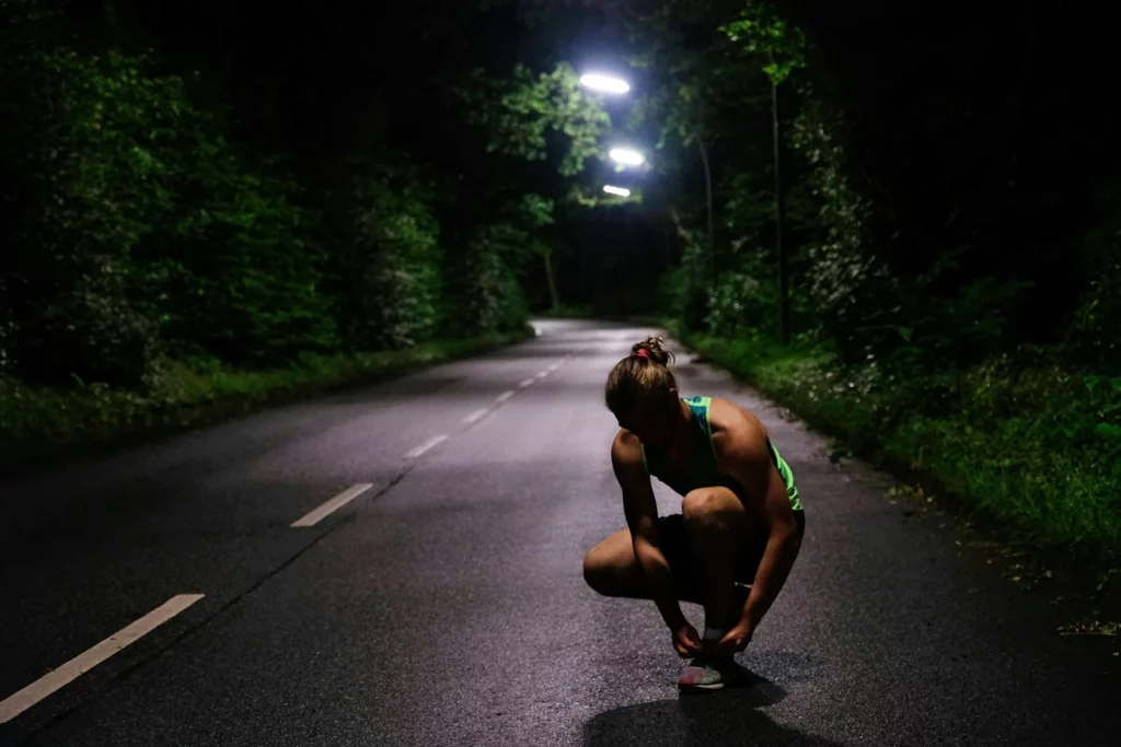 Coureuse arrêtée brièvement sur une route forestière de nuit