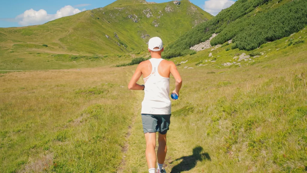 Coureur vu de dos sur un sentier vallonné lors d'une sortie préparatoire